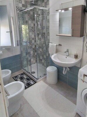 Een bad/douchecombinatie, een haardroger, een bidet, handdoeken