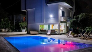 A modern building with a swimming pool, outdoor seating, and a balcony.