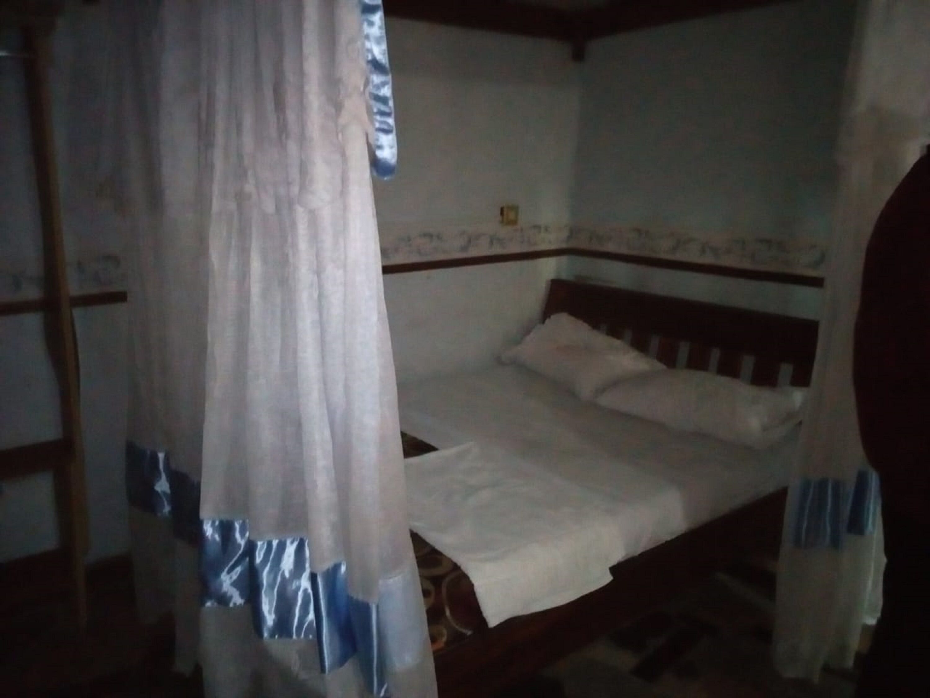 Un dormitorio con cama, cortina y pared con un borde decorativo.