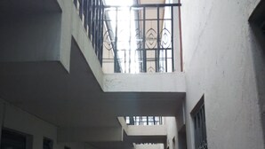 A narrow, multi-level corridor with white walls, metal railings, and a fire extinguisher on the left. - Sunset View Complex (Mombasa)