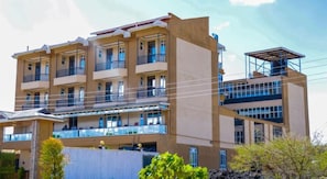 Un hotel de varios pisos con balcones, un espacio exterior cubierto y un tanque de agua.