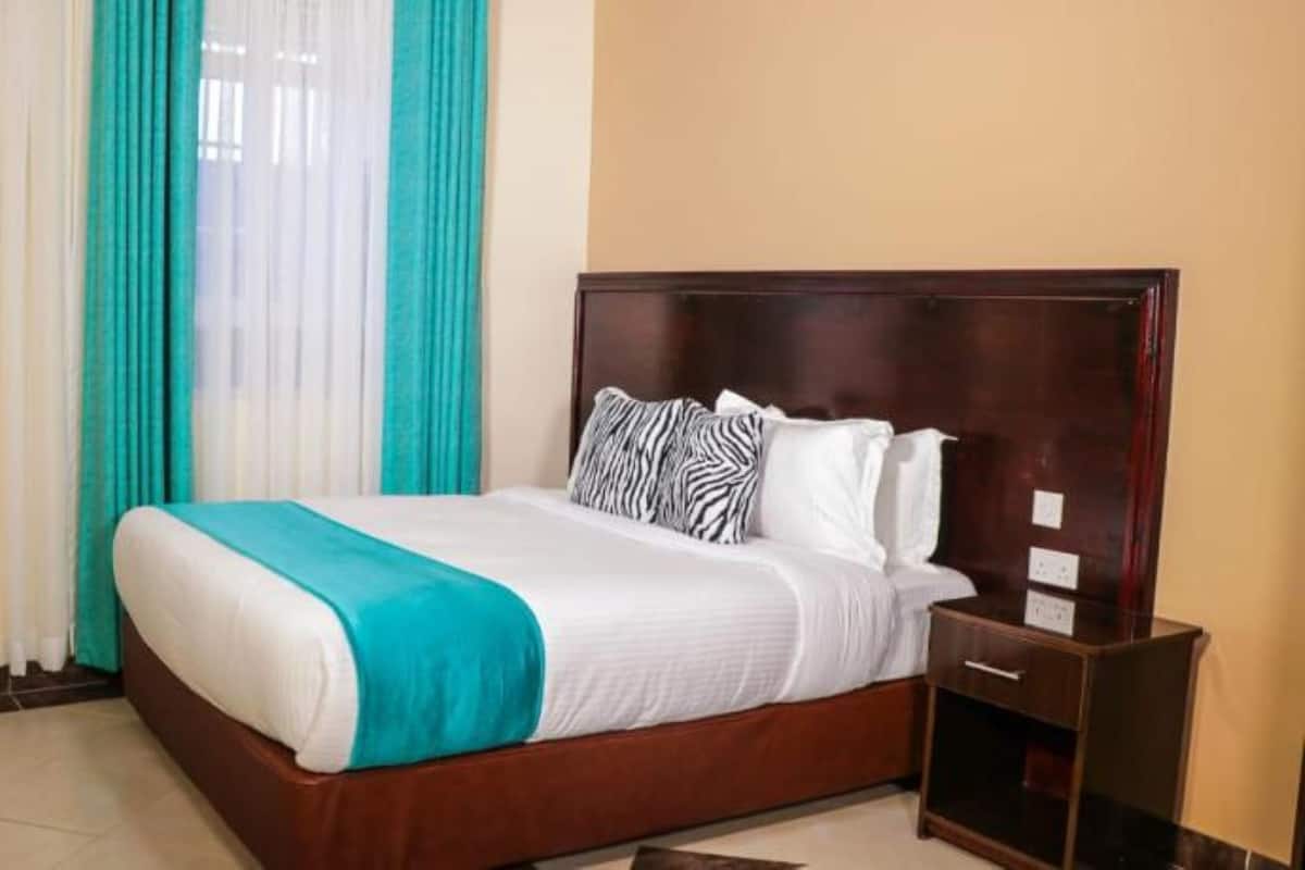 Una habitación de hotel con cama, cortinas y mesita de noche.