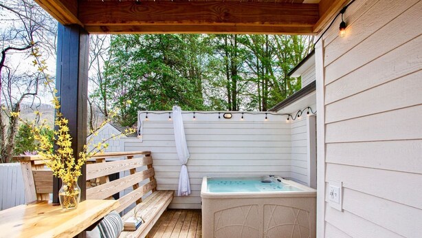 Une terrasse extérieure avec une plateforme en bois, un jacuzzi et un banc en bois.