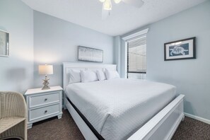 Un dormitorio con cama, mesita de noche, lámpara y decoración en la pared.