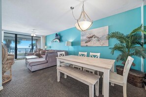 Una habitación con una mesa de comedor, sillas, un sofá, un ventilador de techo y un amplio ventanal con vistas.