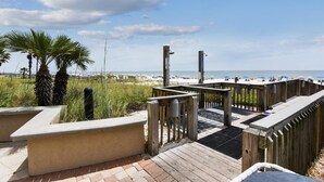 Eine Holzterrasse mit Blick auf Strand und Meer.