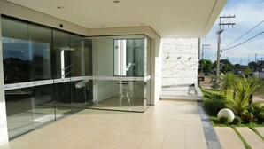 A modern building with glass walls, a tiled floor, and a small garden area with plants and a spherical decoration. - Hotel Portinari (Vilhena)