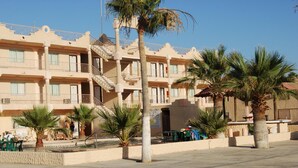 A multi-story hotel with balconies, palm trees, and a pool area. - Hotel Plaza Peñasco (Puerto Peñasco)
