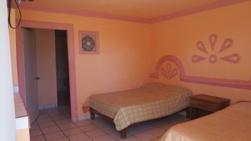 A bedroom with two beds, a door, a fan, and a decorative wall element.