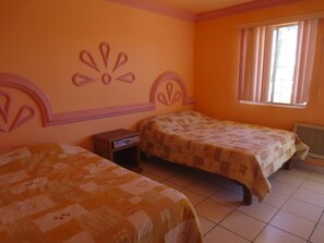 A room with two beds, a window with curtains, and a radiator. - Hotel Plaza Peñasco (Puerto Peñasco)