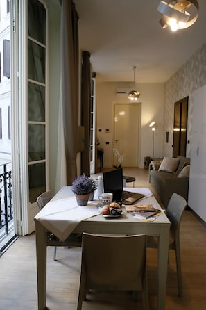 A modern living room with a dining table, a laptop, and a potted plant. - Deluxe Apartment - Napoli Mariana Luxury (Napoli)