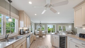 A spacious kitchen with a central island, large windows, and a ceiling fan. - Gorgeous home sleeping 12 with ocean views (West Harwich)
