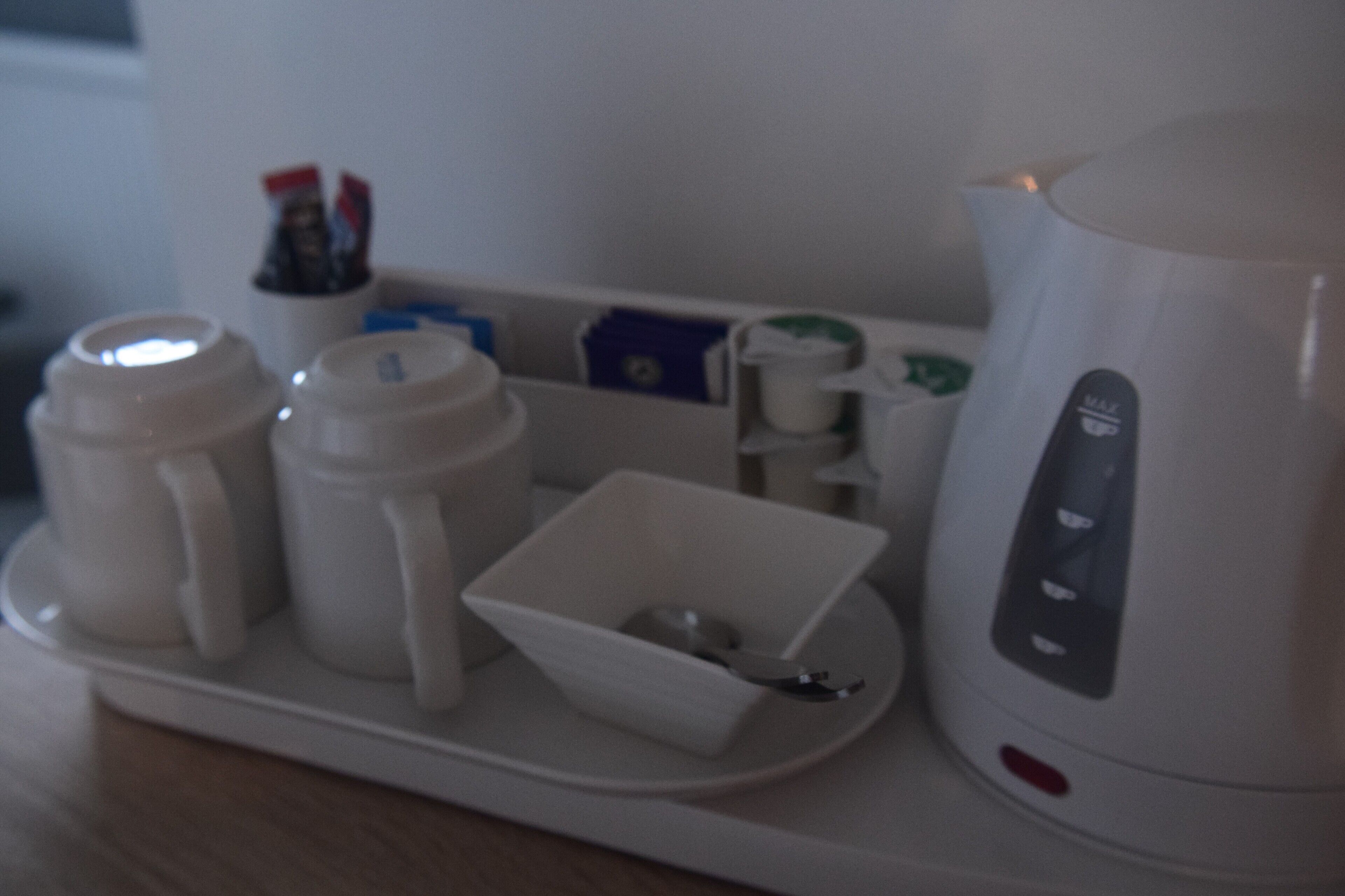 En kaffemaskine, to kopper, en lille skål og en kop kaffe på et fad.
