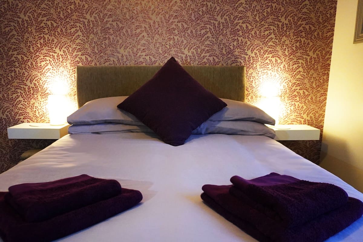 Una cama bien hecha con dos almohadas y dos toallas dobladas.
