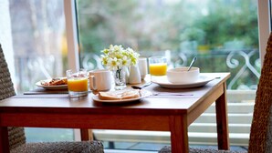 A breakfast table with a plate of toast, a glass of orange juice, a cup, and a vase with flowers. - Borthwen B&B (Dolgellau)
