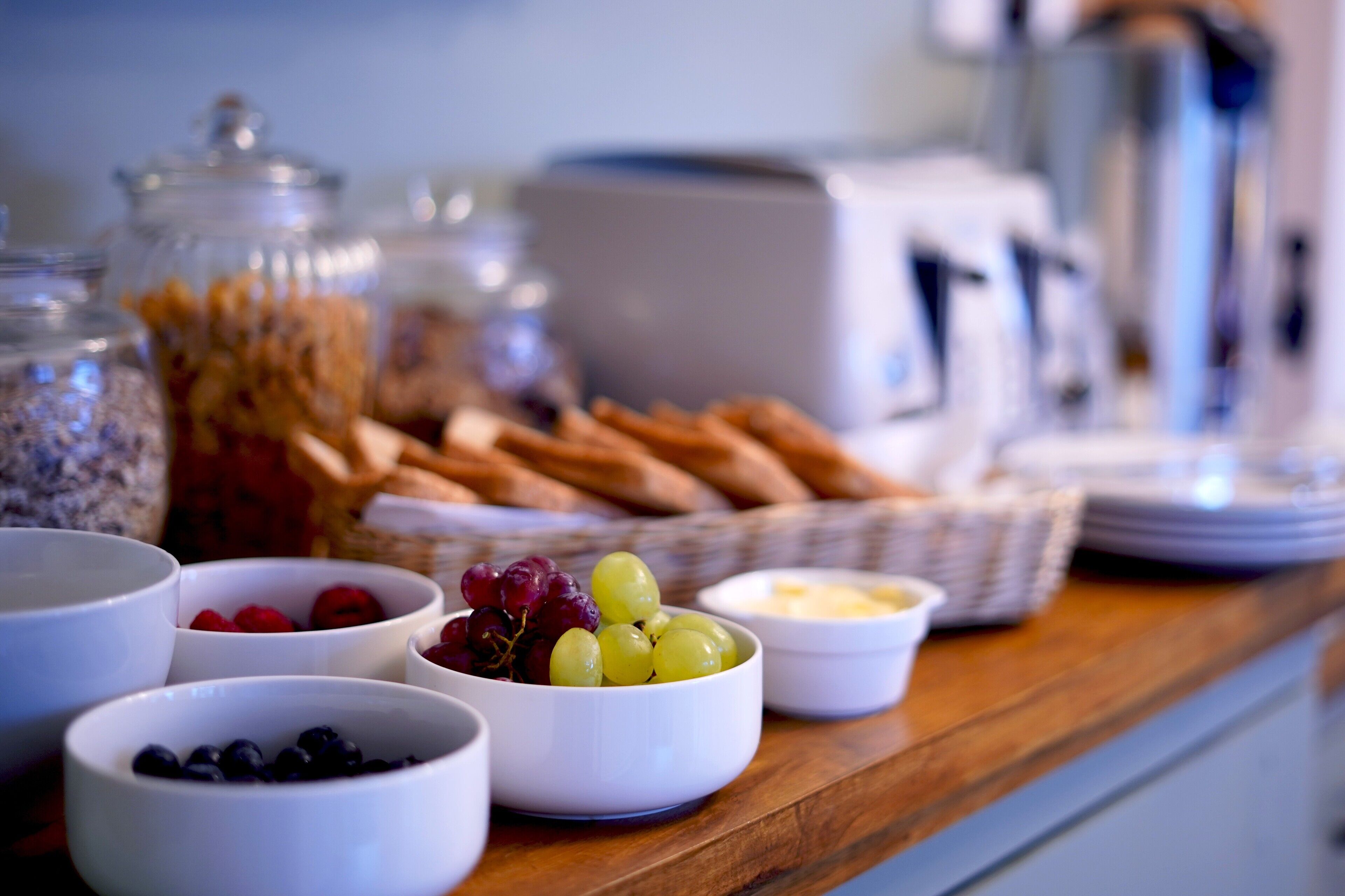 A breakfast buffet with various fruits, cheeses, and bread.