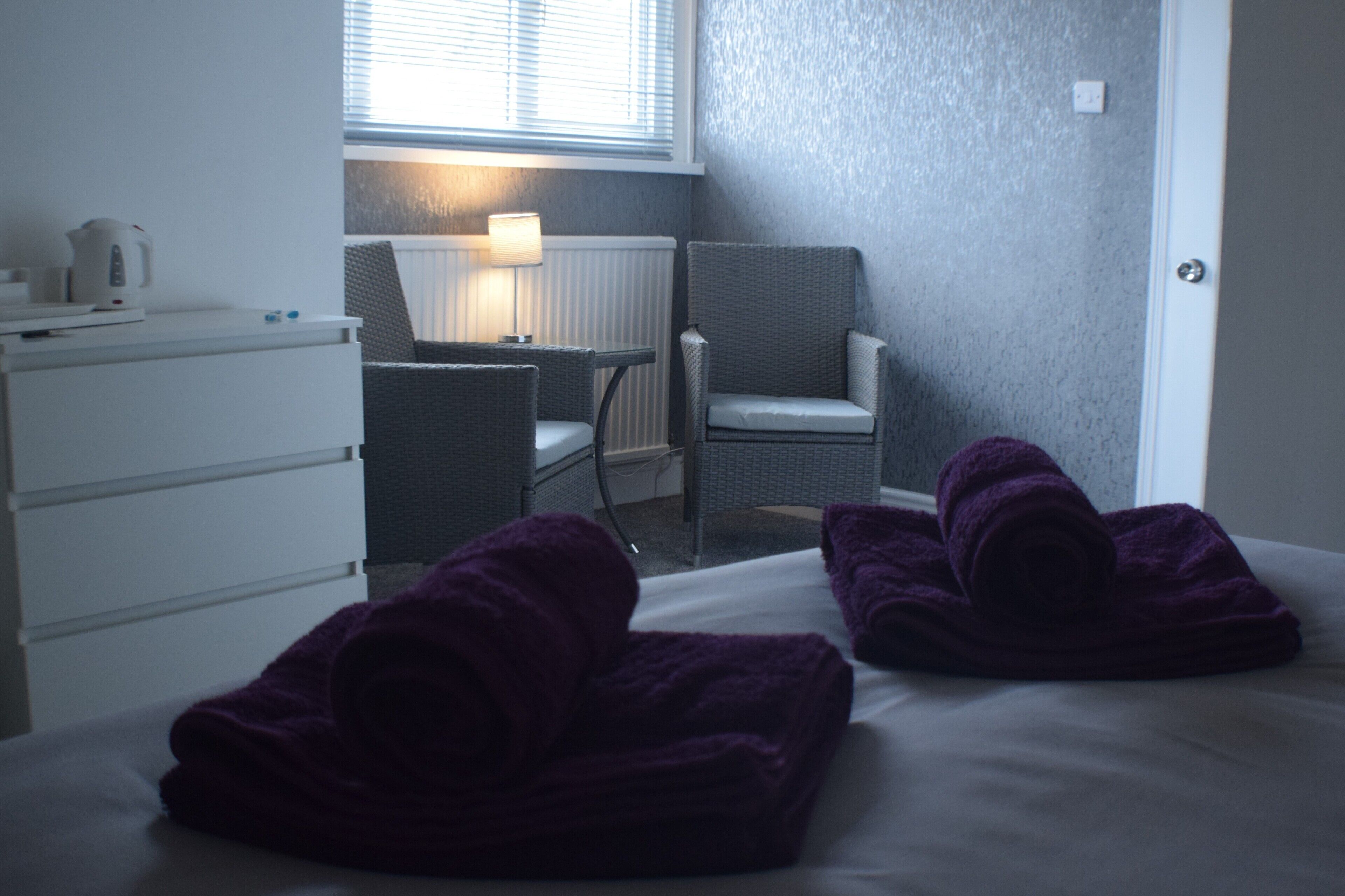 Una habitación de hotel con una cama, dos sillas, una mesa y una lámpara.