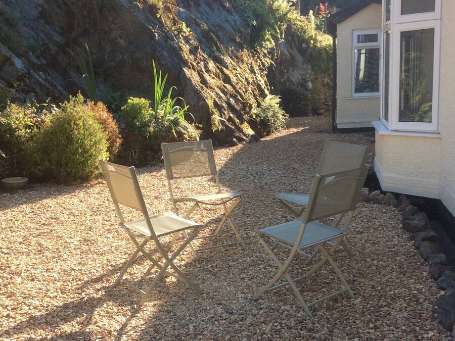 A patio area with two folding chairs and a gravel path leading to a house.