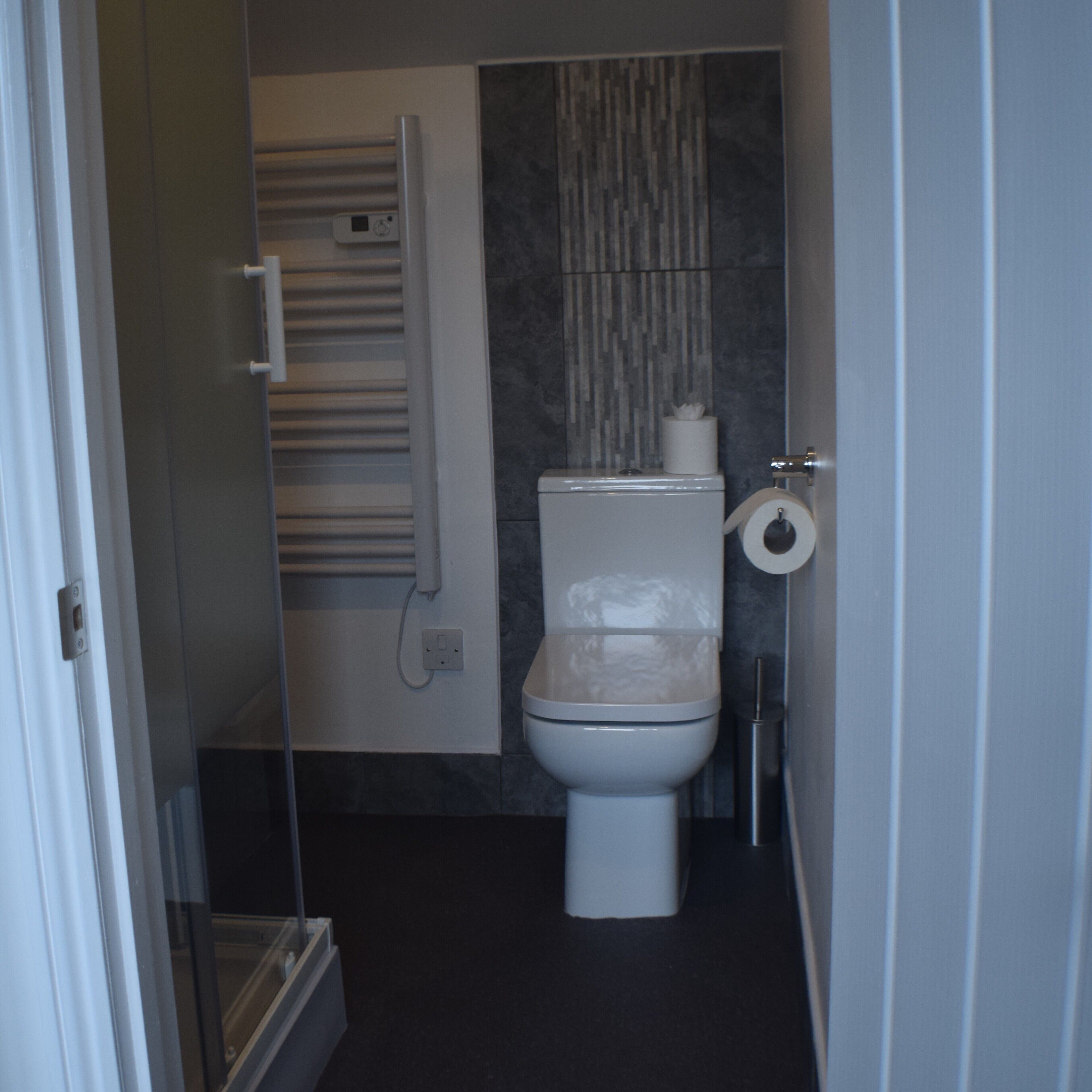 Un baño moderno con inodoro, toallero y dispensador de papel higiénico.