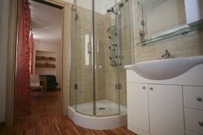 A modern bathroom with a glass-enclosed shower, a white sink, and a mirror above the sink.