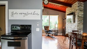 A kitchen with a stainless steel stove, a wall clock, and a sign that reads "Home away from home". - 4-room house with plenty of character (Silverwood)