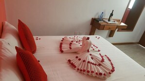 A neatly made bed with a decorative swan pillow and a red pillow. - Limrock Hotel (Machakos)