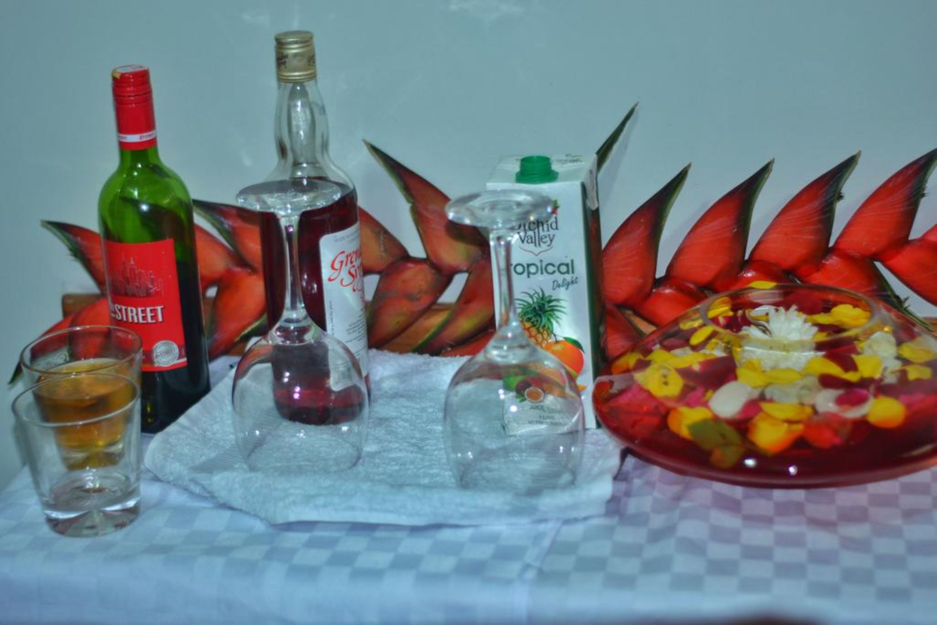 A table with various bottles and a glass of liquid, surrounded by tropical-themed decorations.