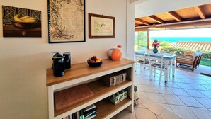 A dining area with a table and chairs, a view of the sea, and a wall with framed artwork. - A 300 mt dalla spiaggia, splendida vista mare, giardino parcheggio grattuito (Costa Rei)