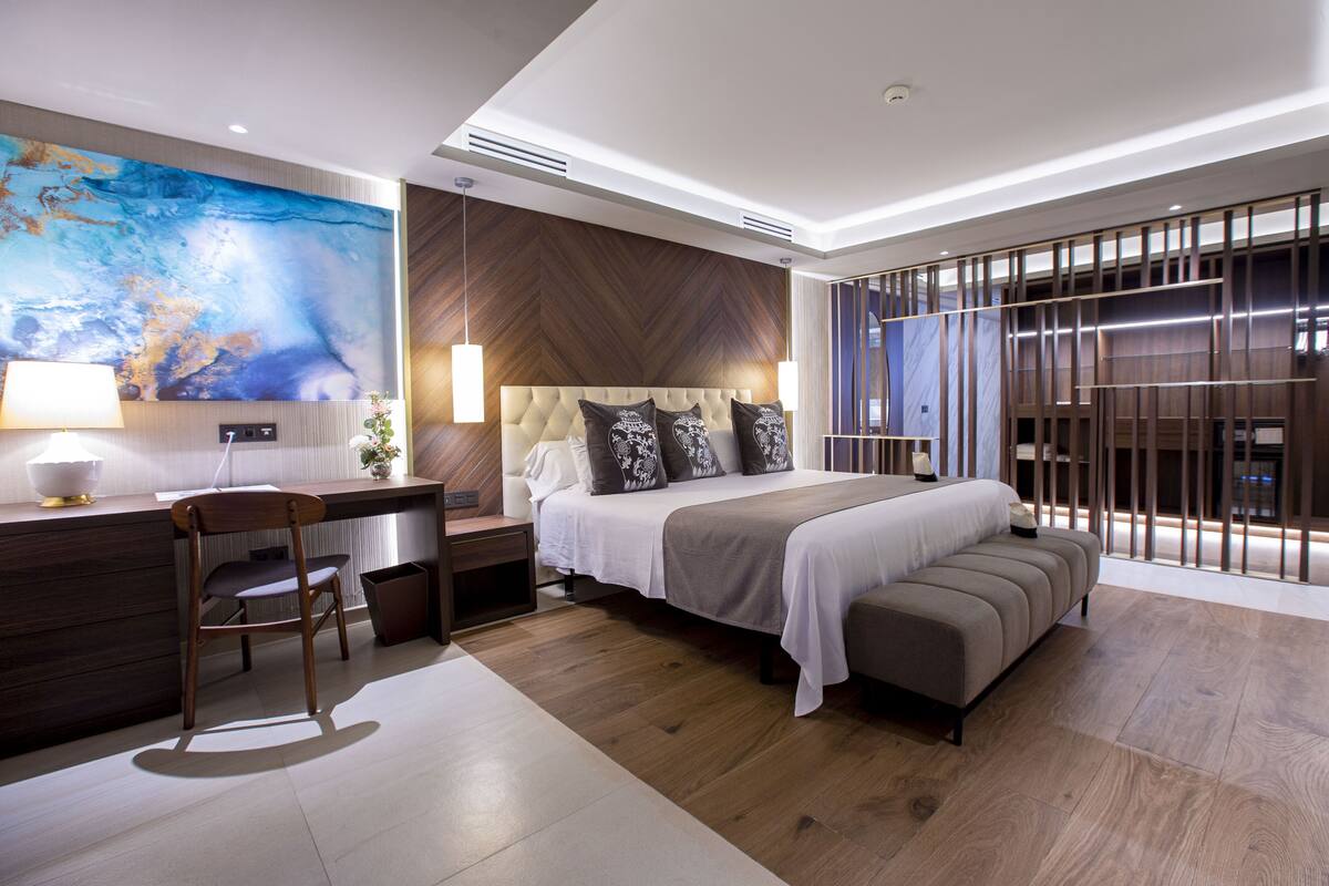 A modern hotel room with a large bed, a desk, and a seating area.