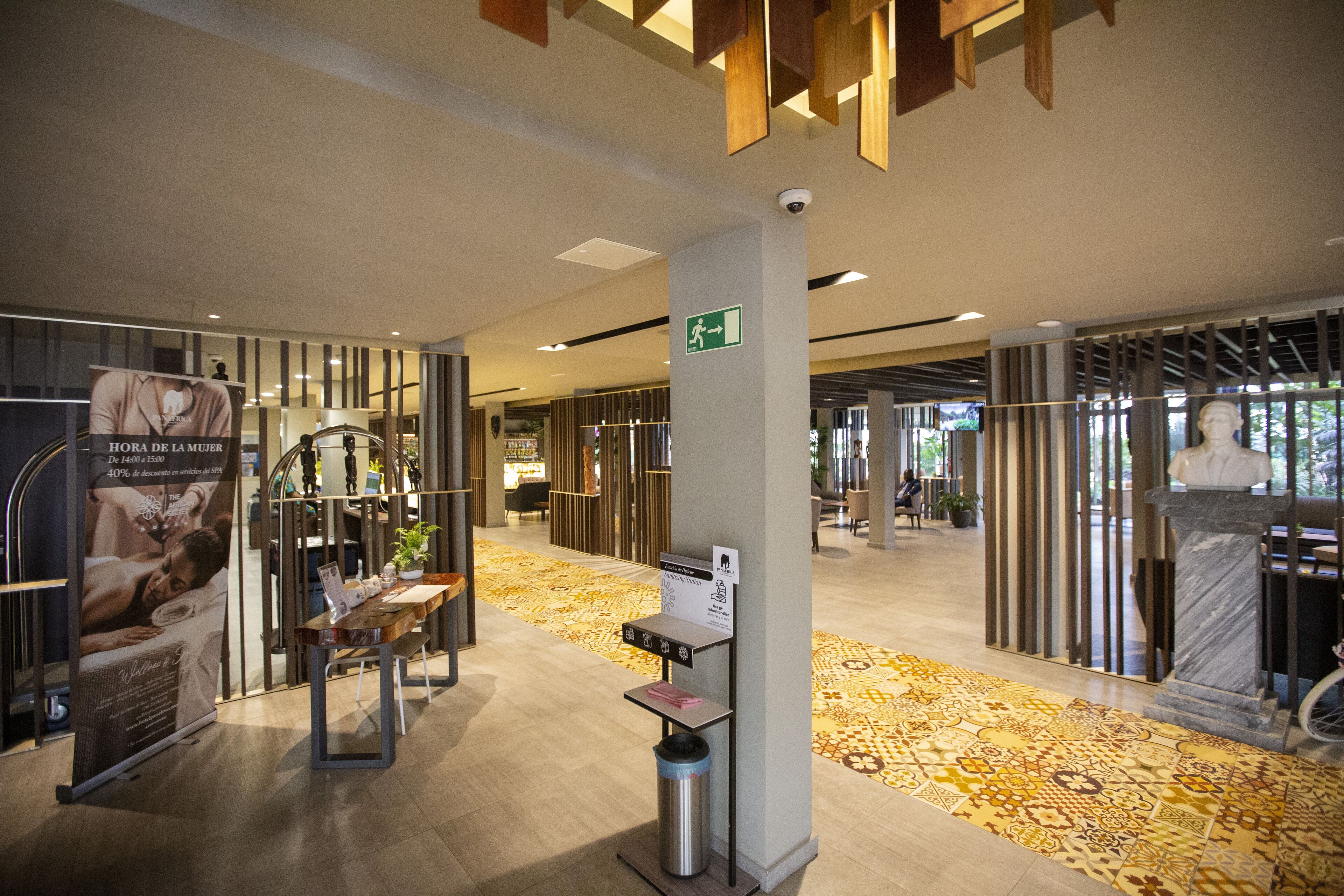 Eine moderne Hotelhalle mit einem gemusterten Teppich, einem Empfangstresen und einer Statue.