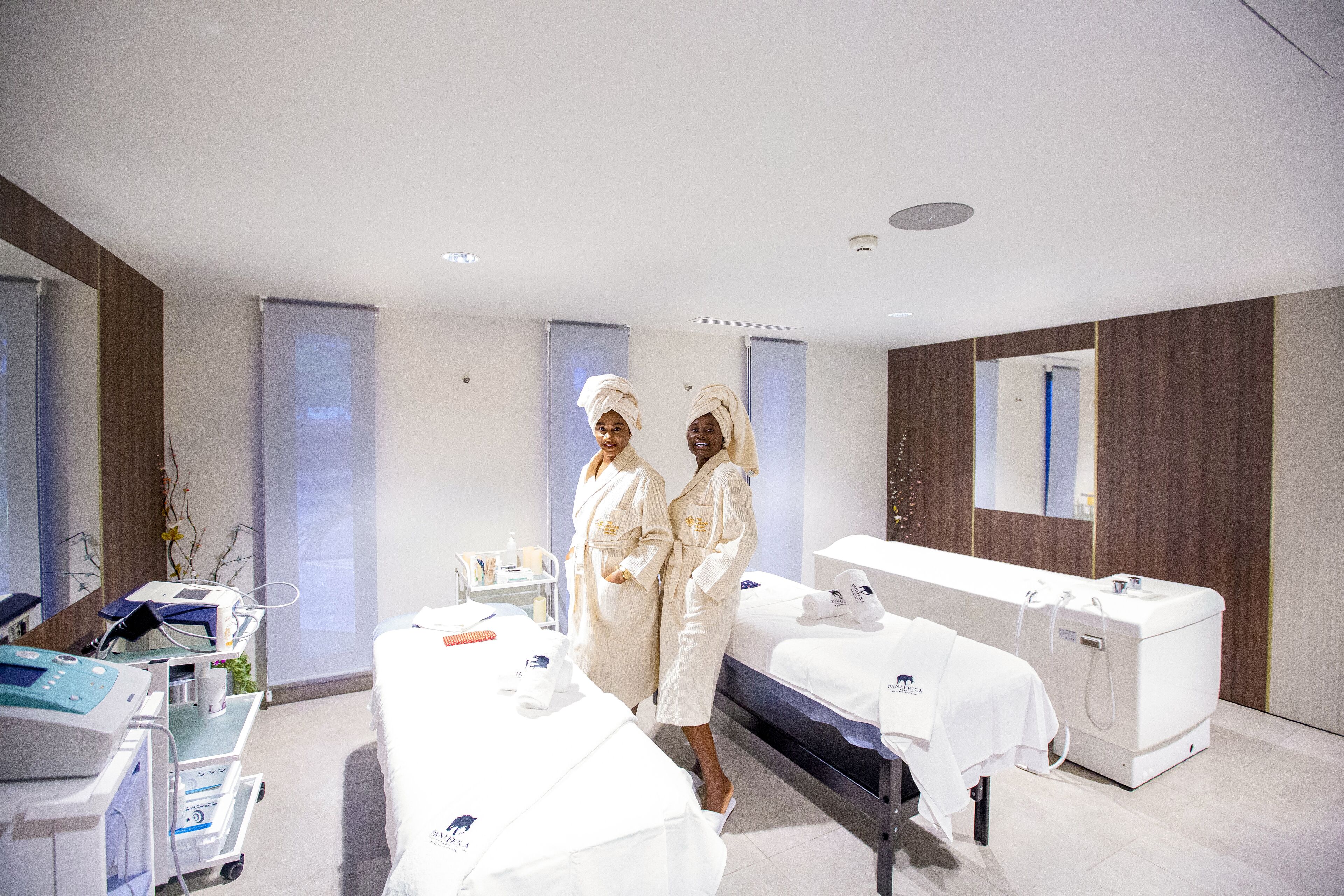 Un moderno spa con dos camillas de masaje, una zona de recepción y un espejo grande.