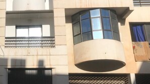A multi-story building with balconies, large windows, and a central cylindrical structure. - Appart Argana (Agadir)