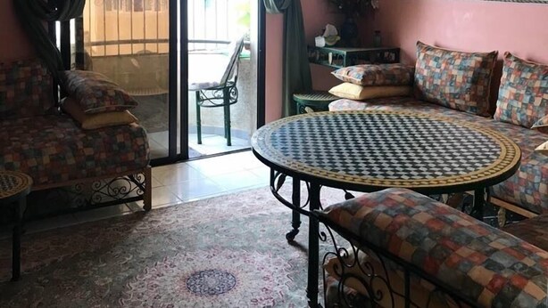 A room with a patterned sofa, a round table, and a decorative ceiling light. - Appart Argana (Agadir)