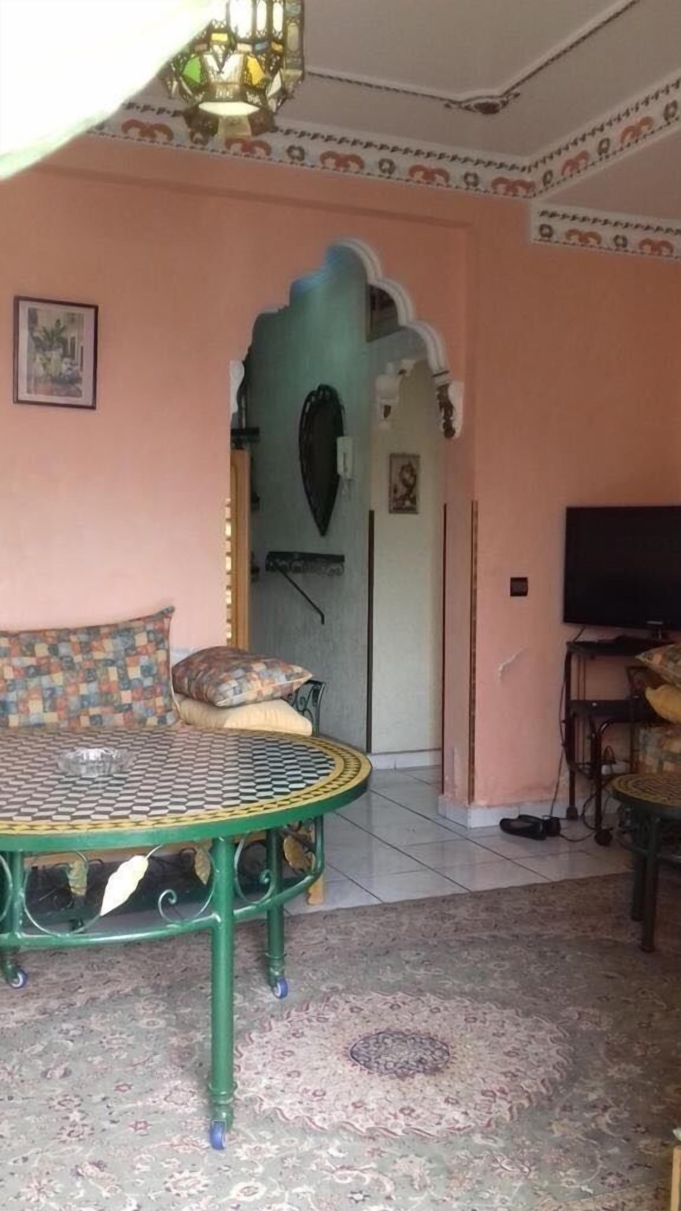 Une pièce avec une table en métal vert, un canapé à motifs, un téléviseur et une moquette à motifs.