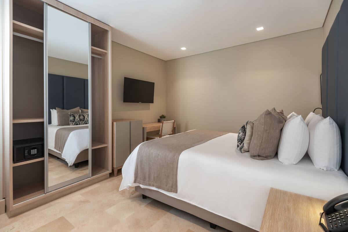 A bedroom with a bed, bedside table, and a wardrobe with a mirror.