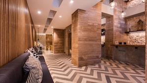A modern lobby with a reception desk, a seating area with a sofa and chairs, and a patterned floor.