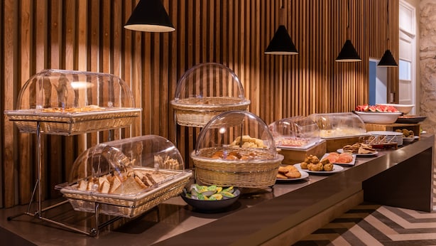 A buffet setup with various food items in clear containers, set against a wooden wall with hanging lights.