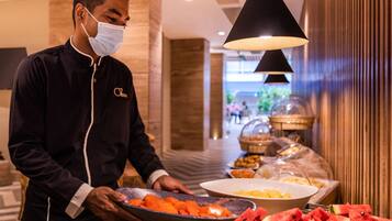 Un membre du personnel de l'hôtel servant des fruits au buffet.