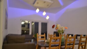 Un comedor con una mesa de vidrio y sillas de madera, un sofá y un jarrón con flores.