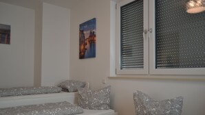 Un dormitorio con una cama, una ventana con persianas, un cuadro en la pared y una escalera.
