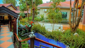 Un pati d'hotel amb un camí empelat, una piscina petita i vegetació al voltant.