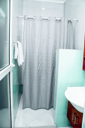 A bathroom with a shower curtain, a glass door, a sink, and a mirror.