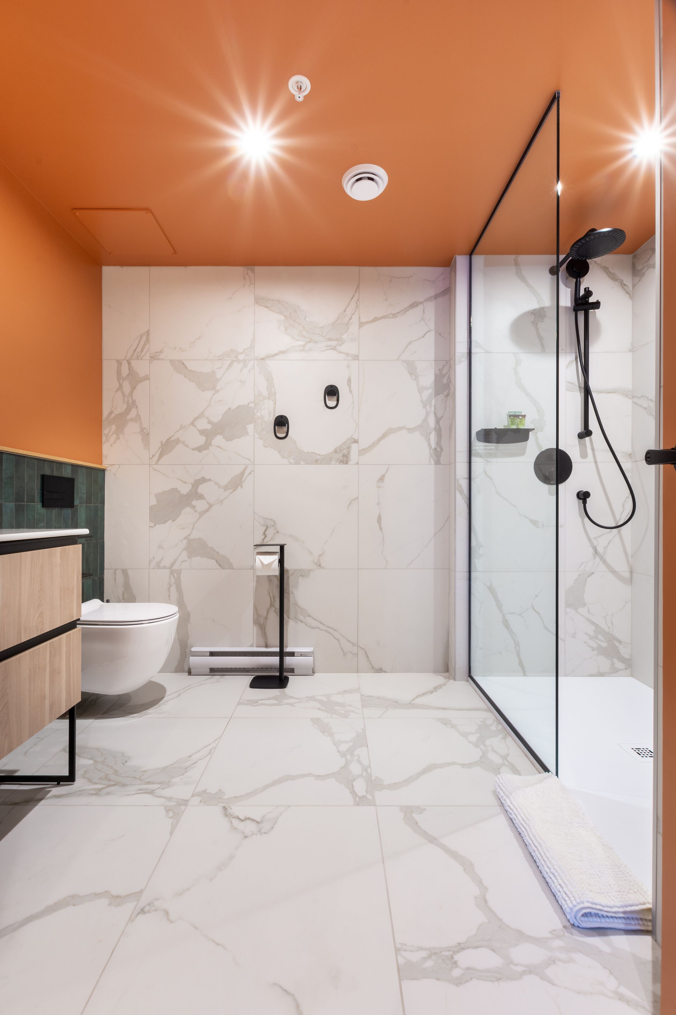 Une salle de bain moderne avec une douche à parois de verre, des toilettes et un meuble-lavabo avec un évier.