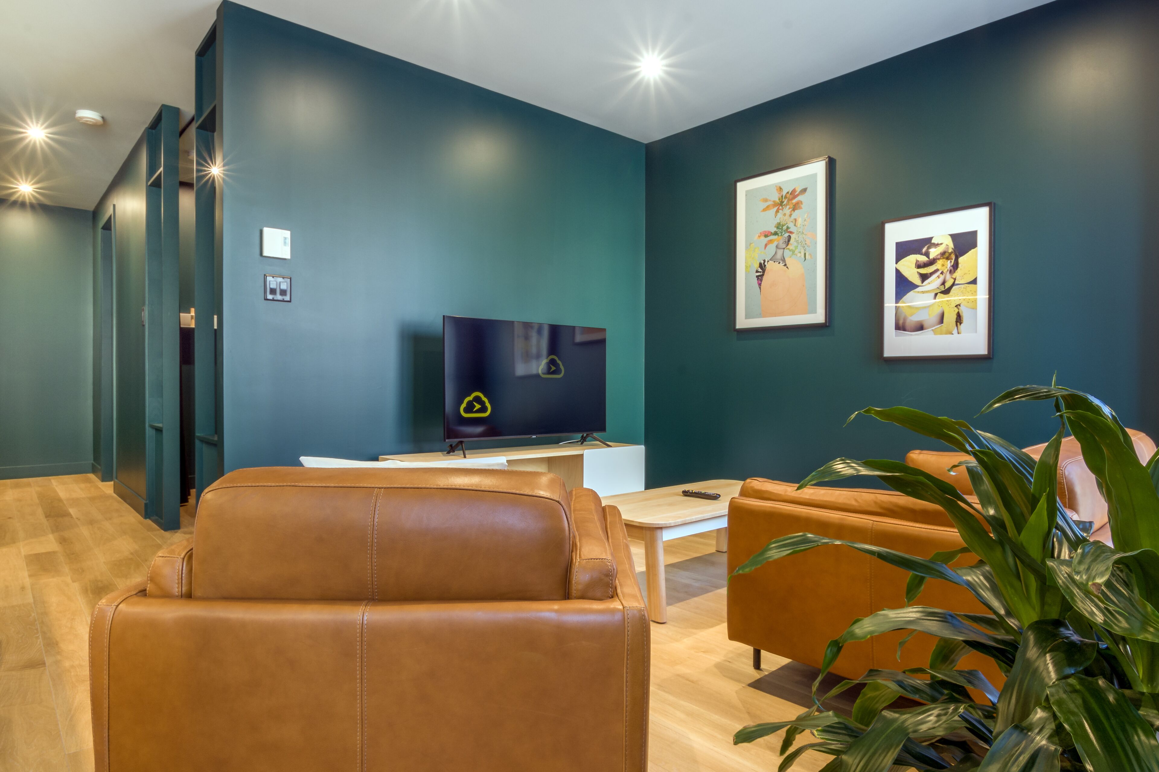 Una sala de estar moderna con un sofá de cuero, una mesa de centro y un televisor sobre un soporte.