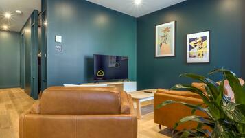 Una sala de estar moderna con un sofá de cuero, una mesa de centro y un televisor sobre un soporte.
