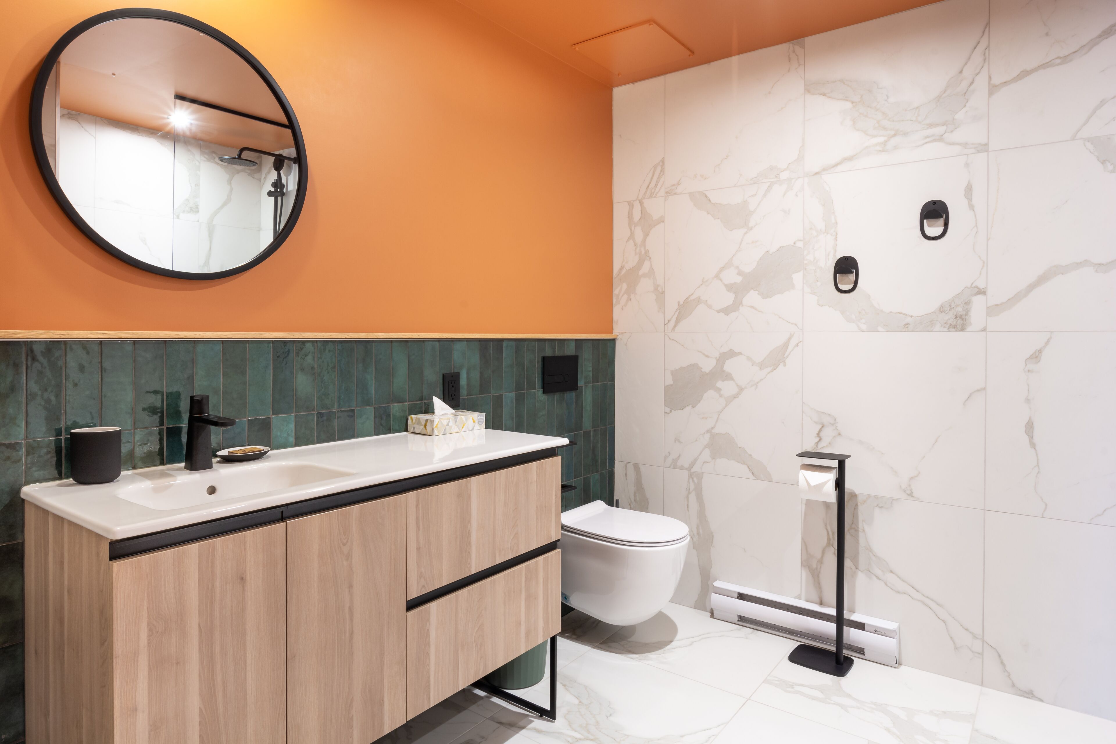 Un bagno moderno con un mobile bagno in legno, uno specchio rotondo, un water e un porta asciugamani.