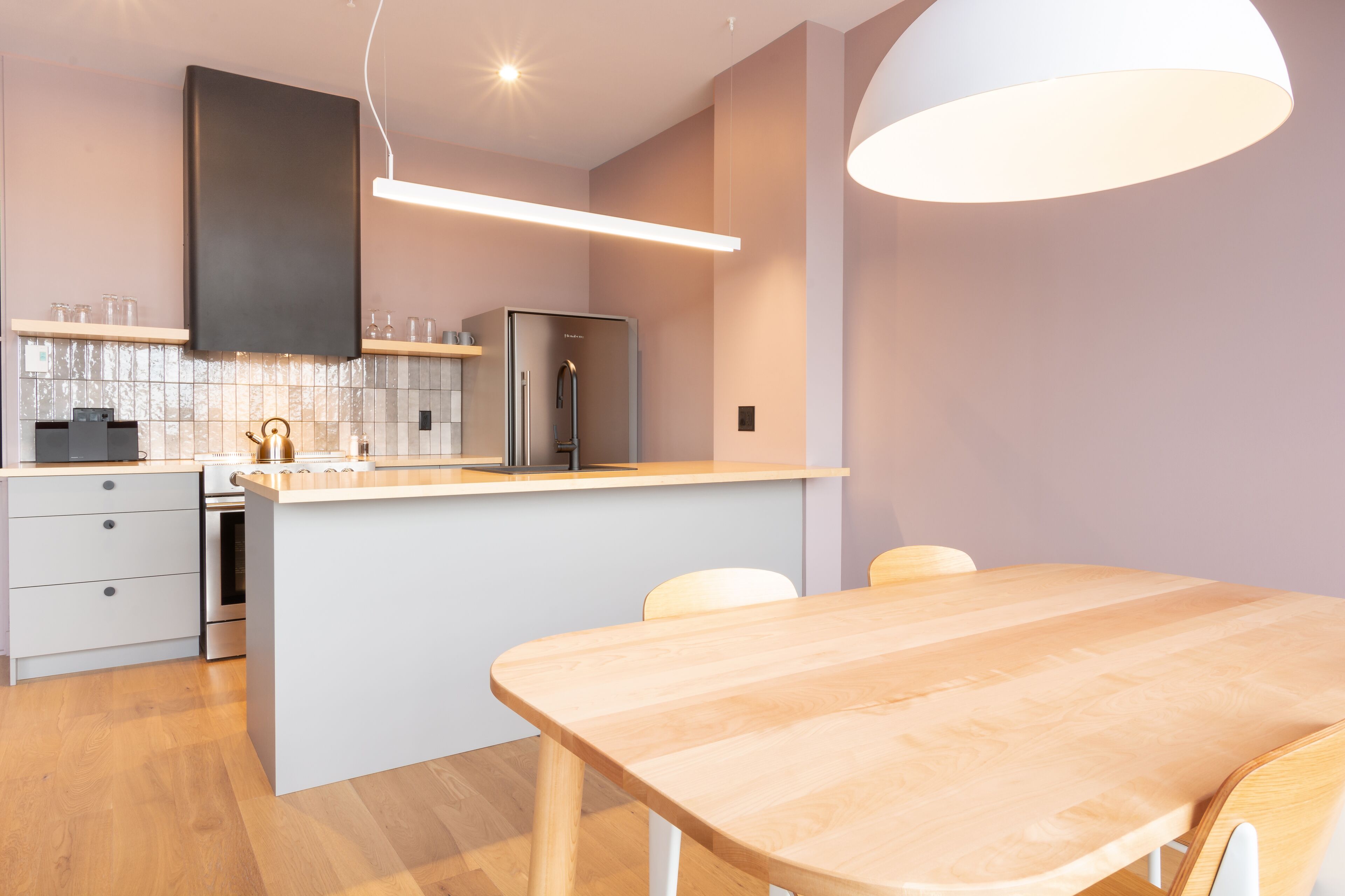 Une cuisine moderne dotée d’un îlot central, d’appareils électroménagers intégrés et d’un coin repas avec une table et des chaises en bois.