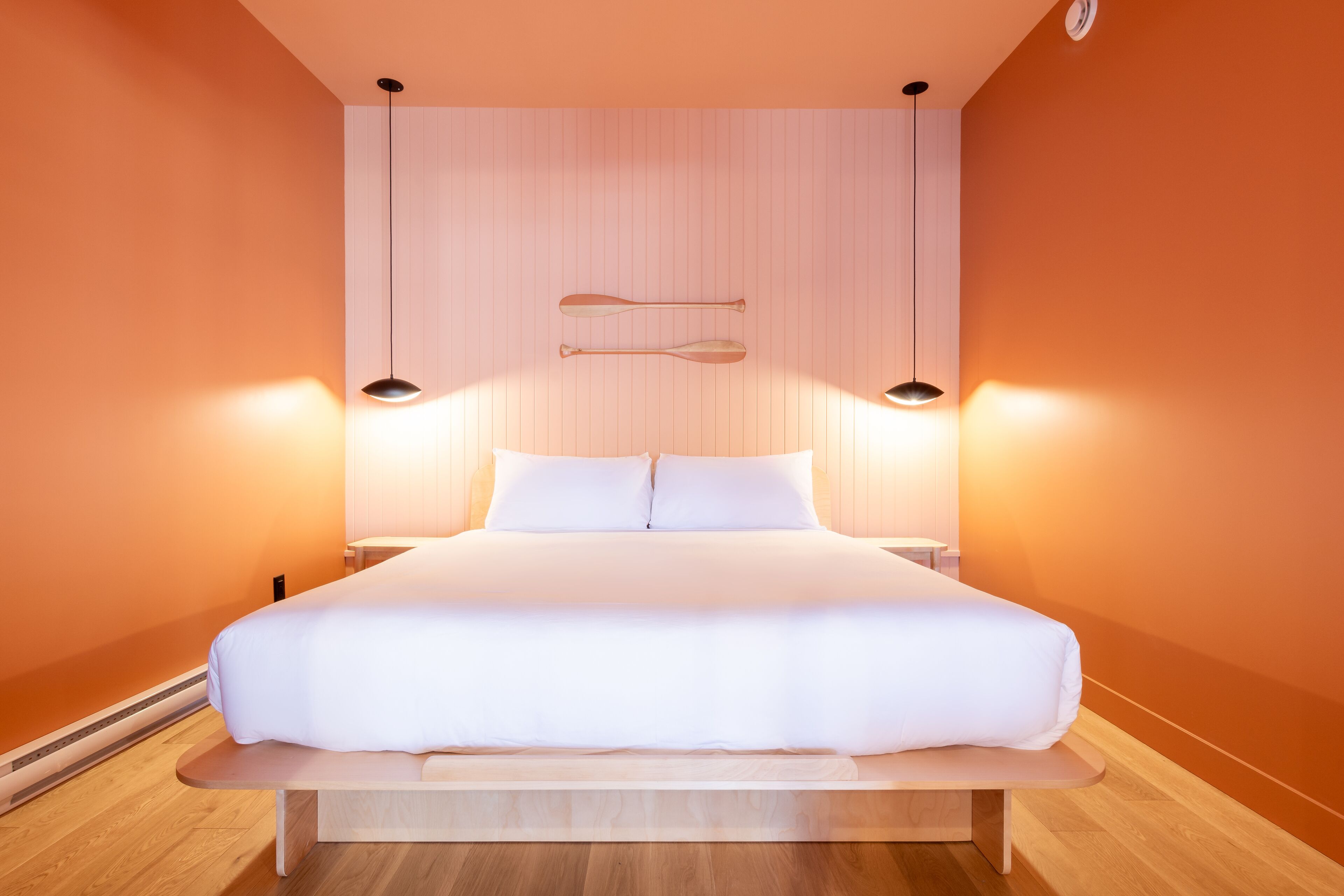 Un dormitorio moderno con una cama grande, cabecera de madera y dos lámparas de pared.