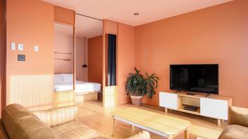 Una sala de estar moderna con un sofá, una mesa de centro, un televisor y una planta en maceta.