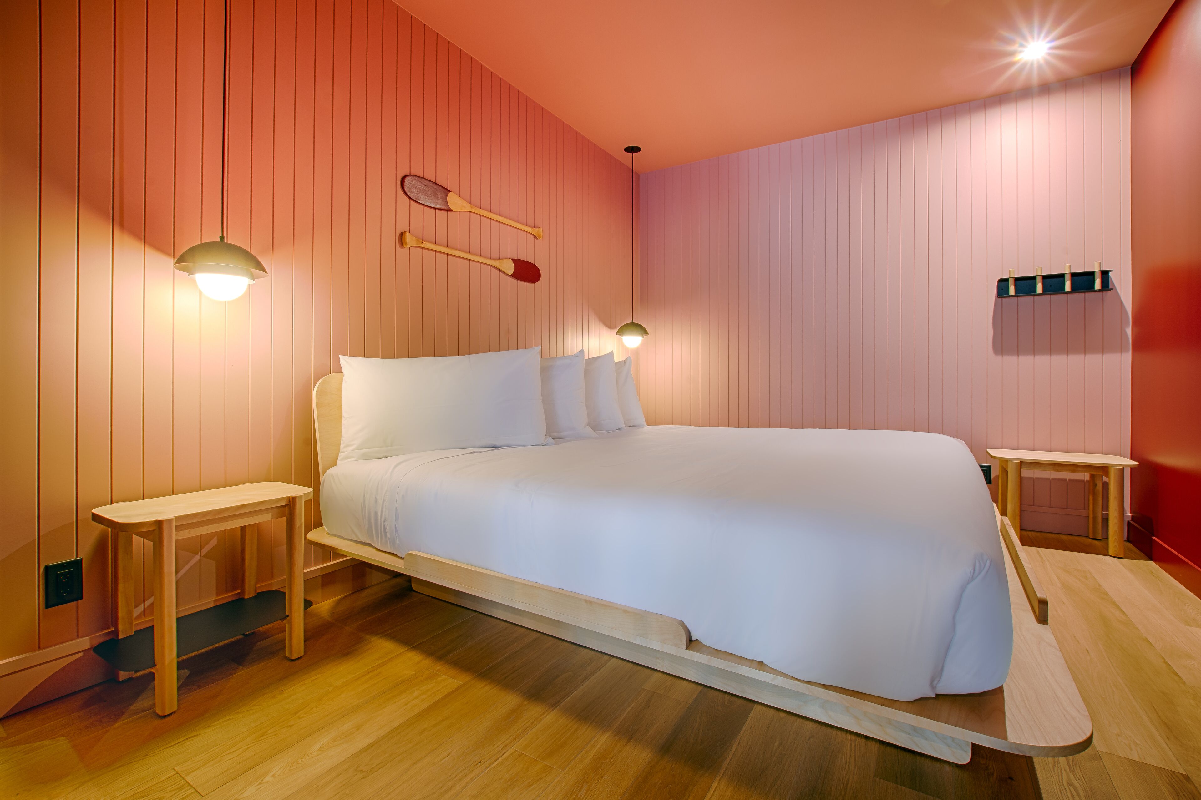 A modern bedroom with a bed, two bedside tables, and a small wooden bench.